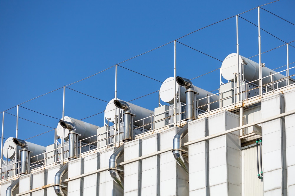 Ventilation pipes on the facade of computer data center. The fragment of the ventilation system against the blue sky. View from the street below